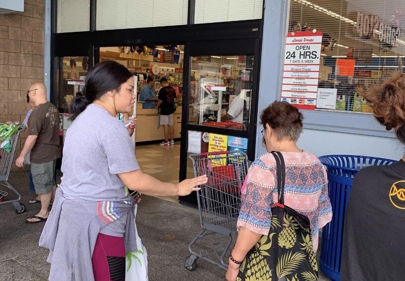 A woman sharing the Gospel and cookies with a shopper outside a store in Hawaii during the Gospel & Cookies outreach