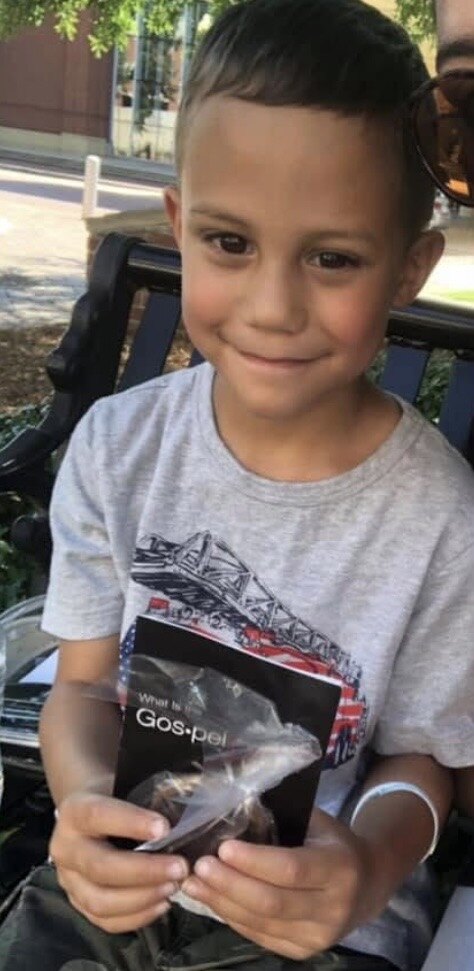 A young boy holding a Gospel tract and a cookie during the Gospel & Cookies outreach